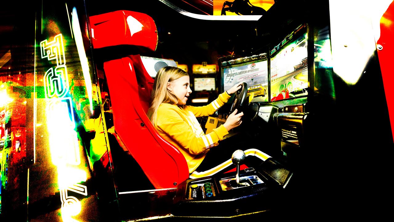 blond flicka kör bil i simulator i spelhuset